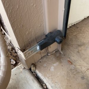 A close-up of a garage door safety sensor installed near the bottom of the door frame by MGG Garage Door Service in San Tan Valley, AZ