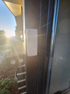 A white garage door sensor or control unit installed on a wall, part of a system by Mountain Fox Garage Doors in Colorado Springs, CO.