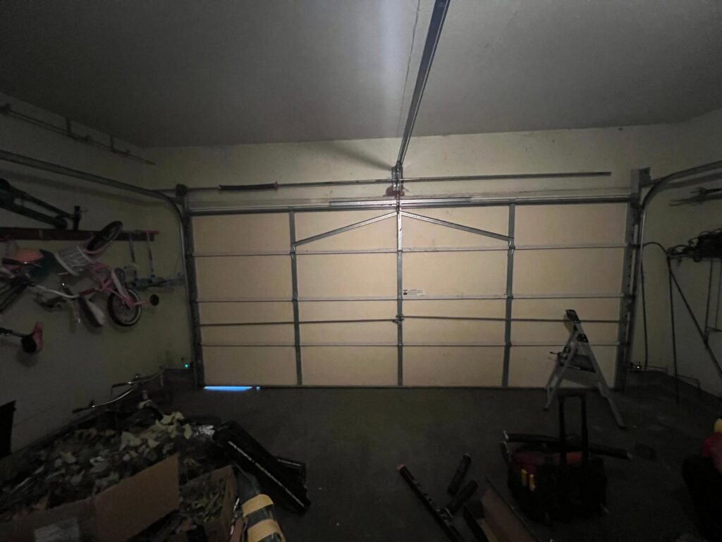 Garage door service in progress with a ladder and tools inside a garage by Lenny's Garage Door in Louisville, KY.
