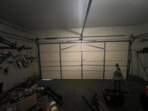 Garage door service in progress with a ladder and tools inside a garage by Lenny's Garage Door in Louisville, KY.