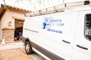 Smokey's Garage Door Company service van parked at a home for a garage door job in Glendale, AZ.
