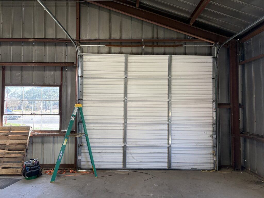 A close-up of a garage door spring system being repaired or installed with a drill, showing detailed work by Cajun Doors & More in Lafayette, LA.