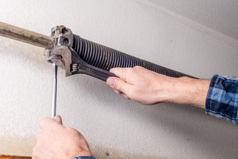A technician performing garage door spring repair or adjustment for Iconic Garage Door Service in Queen Creek, AZ.