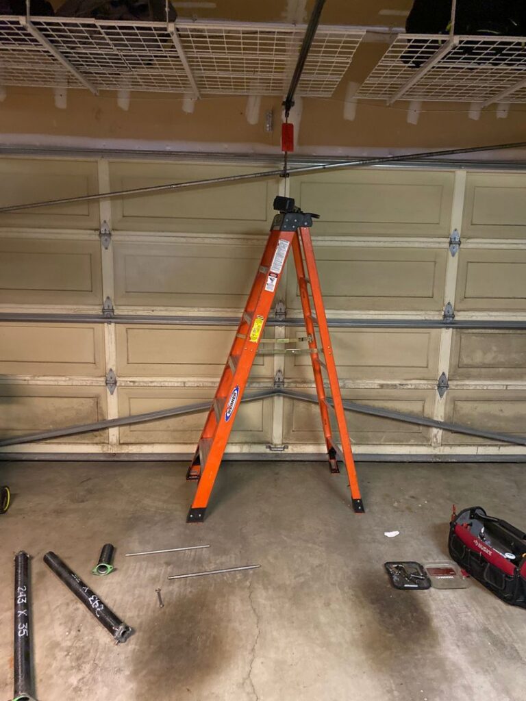 A ladder set up for garage door spring replacement, with new springs and tools on the floor by BSD Garage Door Service in Naperville, IL.