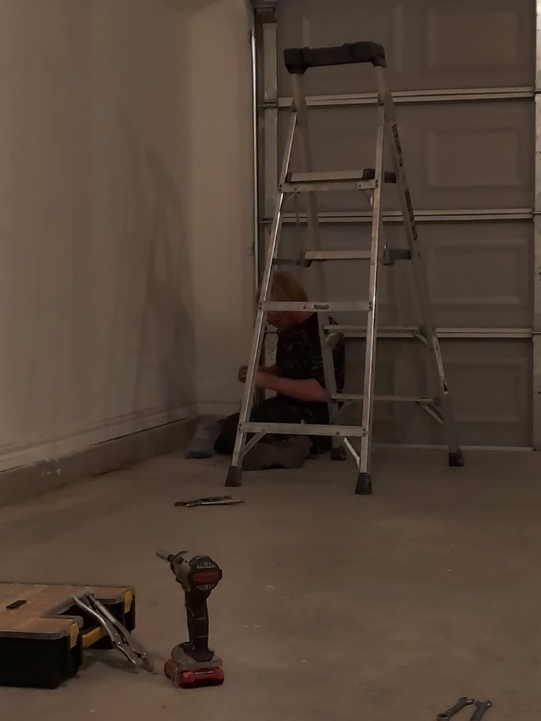 A garage door technician working on-site with tools for Zee's Garage Doors in Oklahoma City, OK.