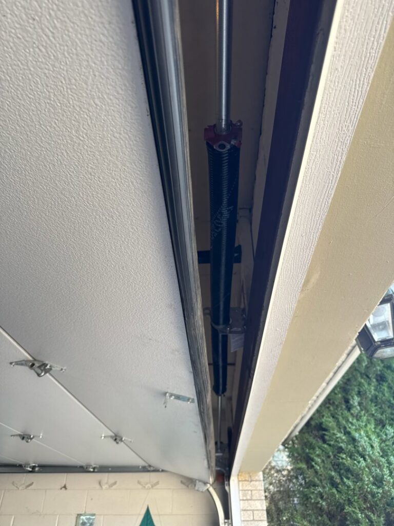 Close-up of a garage door torsion spring and cable system, indicating repair or installation by BSD Garage Door in Naperville, IL