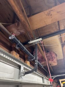 Close-up of a garage door torsion spring and chain drive system, indicating repair or installation by BSD Garage Door in Naperville, IL