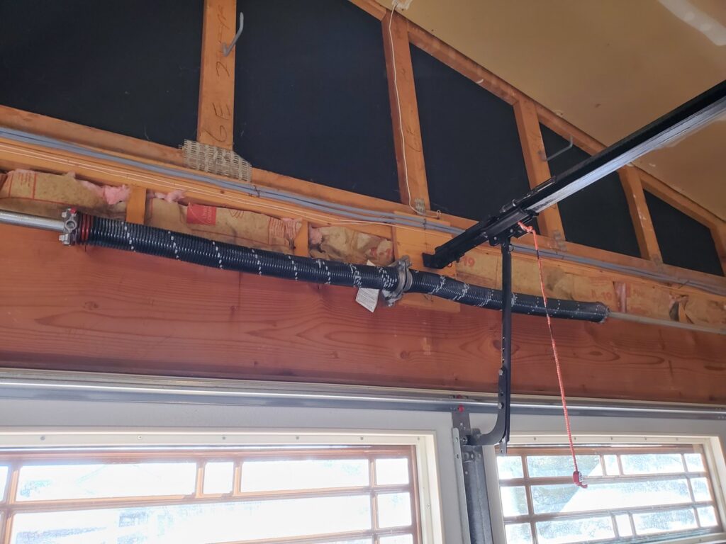 An interior view of a garage door torsion spring system, installed or repaired by Black Forest Door Repair in Colorado Springs, CO.