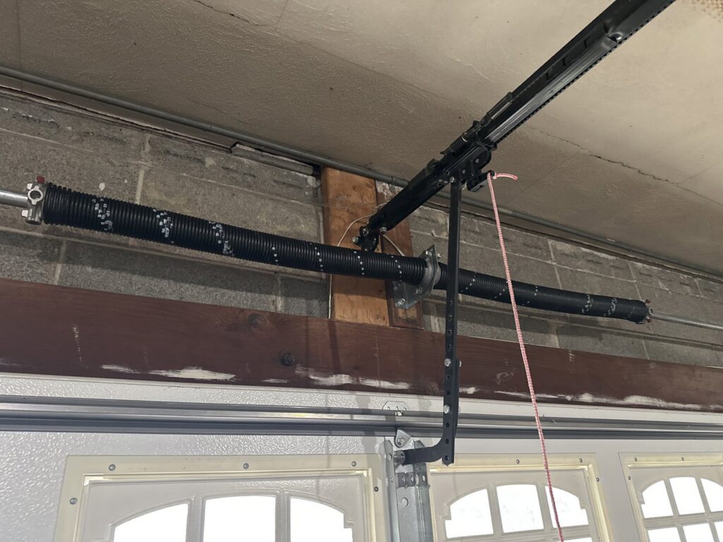 Close-up of a garage door torsion spring system and track, showing repair or installation work by BSD Garage Door in Naperville, IL