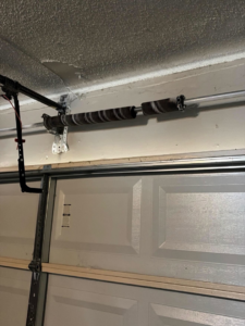 Close-up of a garage door torsion spring system, indicating repair or installation work by J&C Bravo LLC in Cordova, TN.