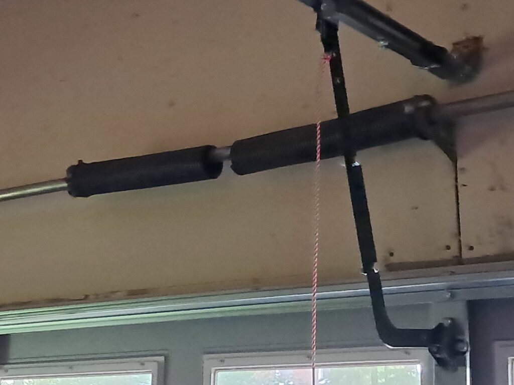Close-up of garage door torsion springs and opener rail, indicating repair or installation by The Birmingham Man Garage Doors in Birmingham, AL.