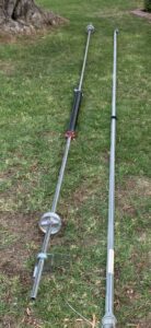 Garage door torsion springs and shaft laid out on the grass, indicating a repair or replacement job by Fix It Now Garage Doors.com in Tempe, AZ.