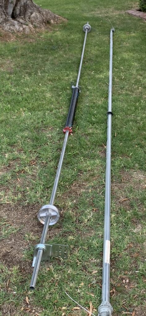 Garage door torsion springs and shaft laid out on the grass, indicating a repair or replacement job by Fix It Now Garage Doors.com in Tempe, AZ.