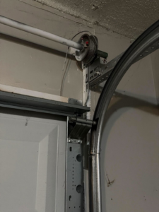 Detail of a garage door track, pulley, and cable system, showing components serviced by J&C Bravo LLC in Cordova, TN.