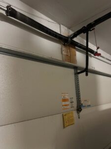 Interior view of a garage door showing the track, rollers, and a service sticker from BSD Garage Door in Naperville, IL