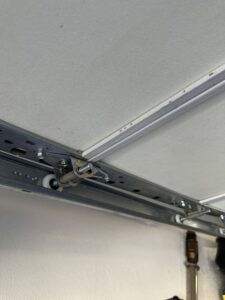 Close-up view of a garage door track and roller system, indicating repair or maintenance by Absolute Garage Doors LLC AZ in Mesa, AZ