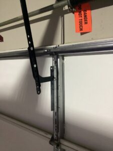 Close-up of a garage door track and spring mechanism with a danger tag, showing work by CCM Overhead Doors in Oklahoma City, OK.