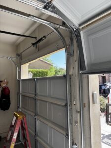 An interior view of a garage door, showing the tracks, springs, and a ladder, indicating a repair or installation job by 101 Garage Doors in Phoenix, AZ.