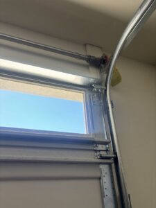 Close-up of a garage door's upper track and roller, highlighting components serviced by 101 Garage Doors in Phoenix, AZ.