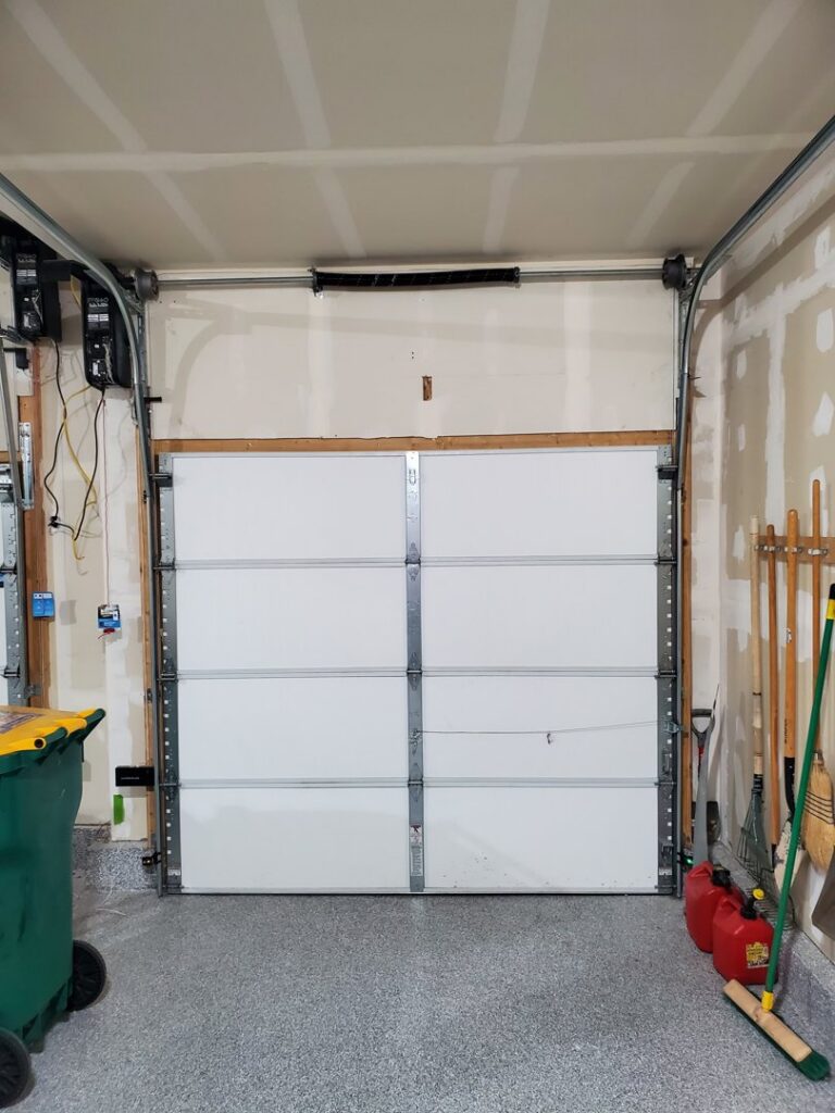 An interior view of a white sectional garage door, possibly awaiting opener installation by Black Forest Door Repair in Colorado Springs, CO.