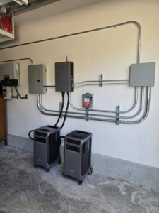 An indoor garage electrical panel and conduit installation with power stations by Ride the Lightning Electrical Services in El Cajon, CA.