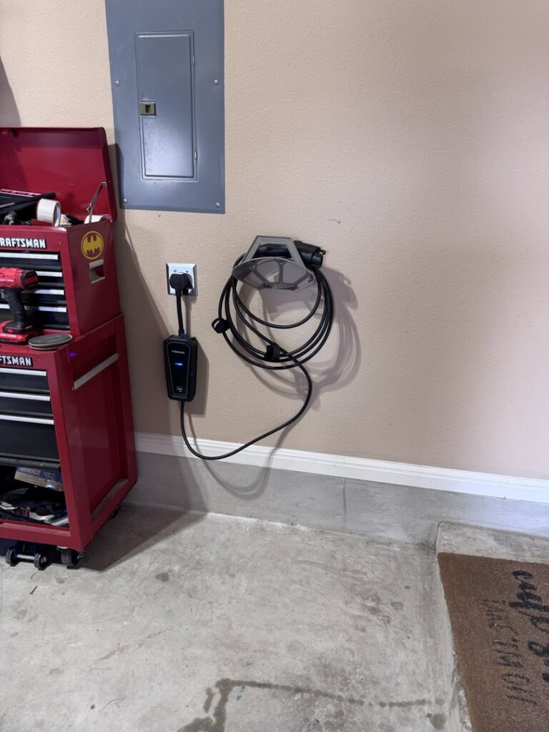 An EV charger installed in a garage next to an electrical panel and toolbox, showcasing work by Davis Electric in Cleveland, OH.
