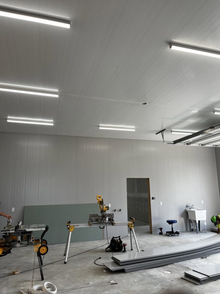 Fluorescent strip lights installed on the ceiling of a garage or workshop under construction, a service by Superior Electrical Solutions llc in Clear Spring, MD.