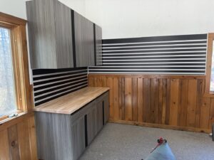 A clean garage interior featuring a newly installed light-colored carpet and custom storage cabinets by GarageExperts of Fox Valley in Kaukauna, WI.