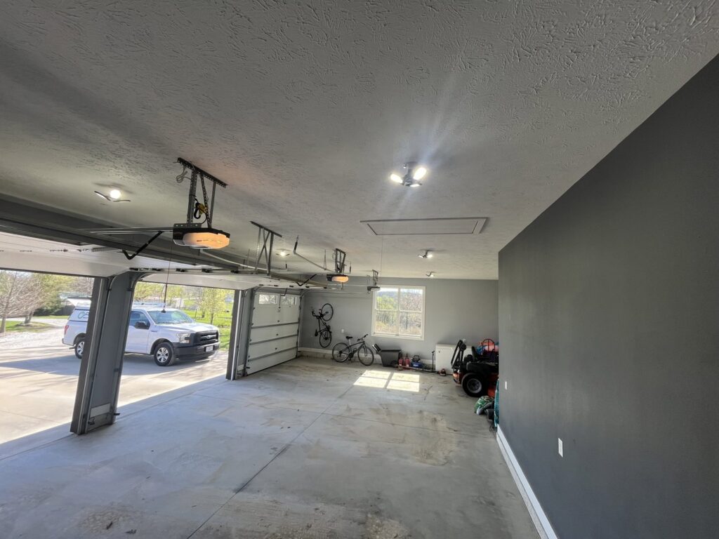 Garage interior with new ceiling lighting and garage door openers installed by Powered Electrical & Lighting Services LLC in Springfield, MO.