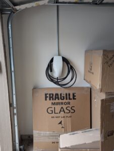 A Tesla EV charger installed in a garage with electrical conduit, demonstrating professional service by Davis Electric in Cleveland, OH.