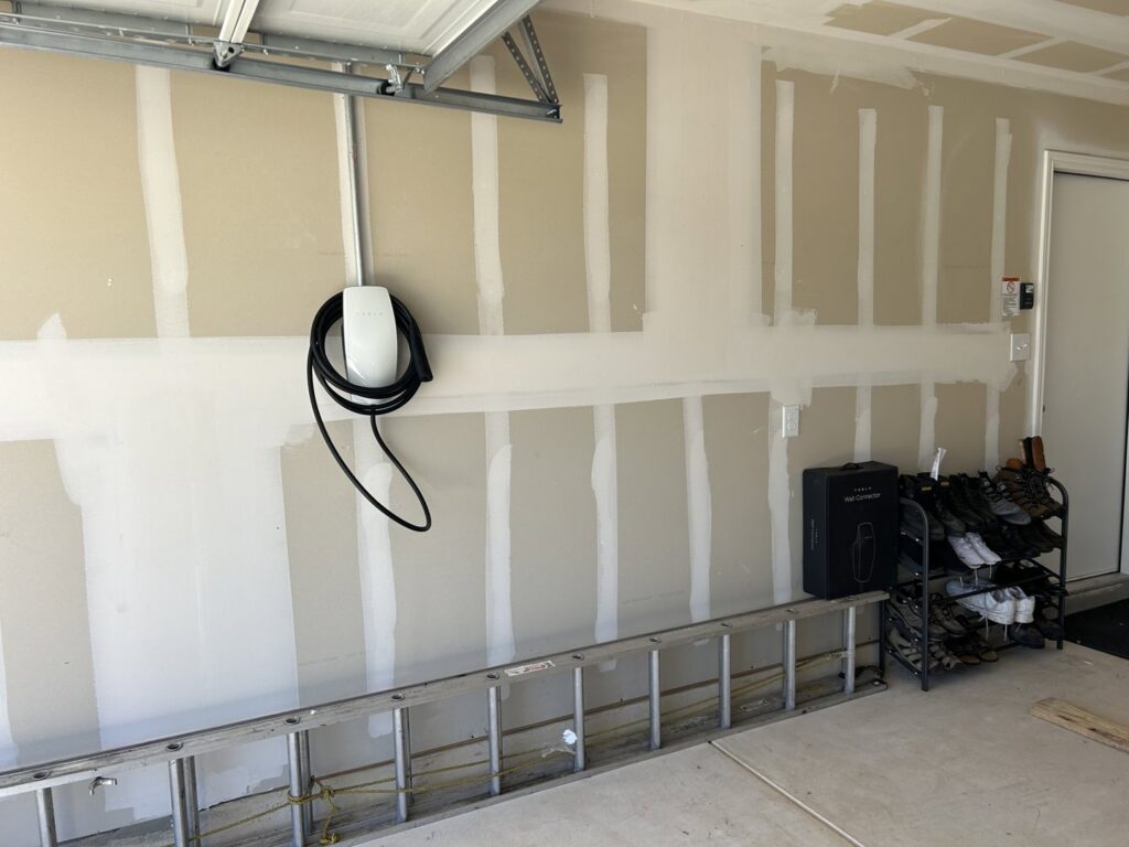 A Tesla EV charger installed in a garage, with a ladder nearby, showcasing electrical work by Davis Electric in Cleveland, OH.