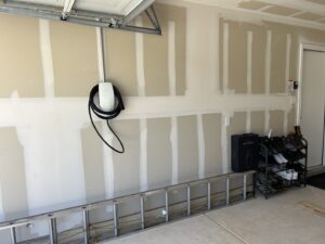 A Tesla EV charger installed in a garage, with a ladder nearby, showcasing electrical work by Davis Electric in Cleveland, OH.
