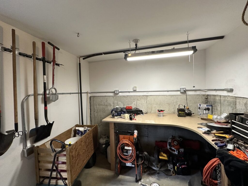 Surface-mounted electrical conduit and fluorescent lighting installed in a garage or workshop by RAD-WIRE ELECTRIC, LLC in Manchester, NH.