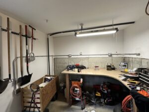 Surface-mounted electrical conduit and fluorescent lighting installed in a garage or workshop by RAD-WIRE ELECTRIC, LLC in Manchester, NH.