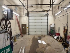 A garage or workshop showing exposed electrical conduit, fluorescent lighting, and a wall-mounted heater, installed by SEI Electric Inc. in Idaho Falls, ID.