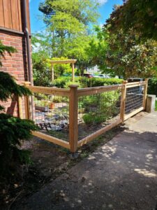 A garden enclosure featuring a wooden frame and wire mesh panels by Helmco Fences in Seattle, WA.