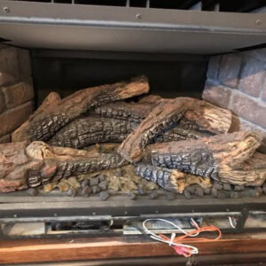 A close-up view of gas fireplace logs and burner components, showing detailed work by Precision Energy LLC in Everett, WA.