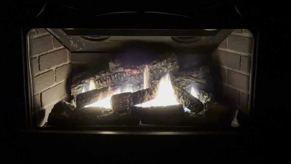 A gas fireplace with warm flames glowing in a dark room, highlighting a heating service from Precision Energy LLC in Everett, WA.