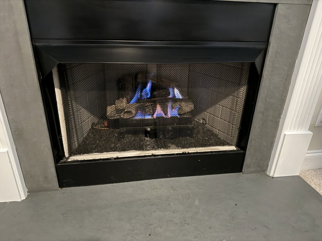 A gas fireplace with blue flames, indicating a heating system inspection by Komfort Air Service Experts in Charlotte, NC.