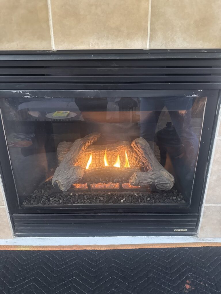 A cozy gas fireplace with artificial logs and flames, installed by Nevada Heating Reno in Sparks, NV.