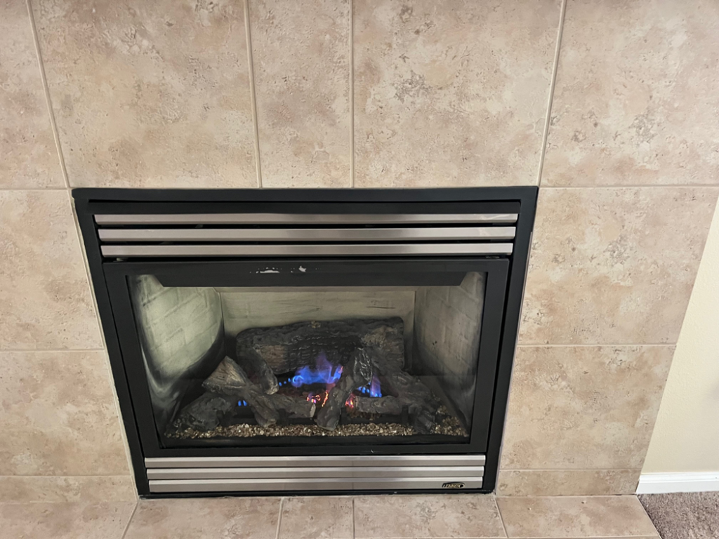 A modern gas fireplace with blue flames, installed in a tiled wall by Precision Energy LLC in Everett, WA.