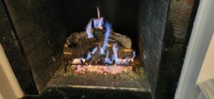 A gas fireplace with artificial logs and vibrant blue flames, serviced by Professional Fireplaces and Chimney Sweeps in Huntsville, AL.