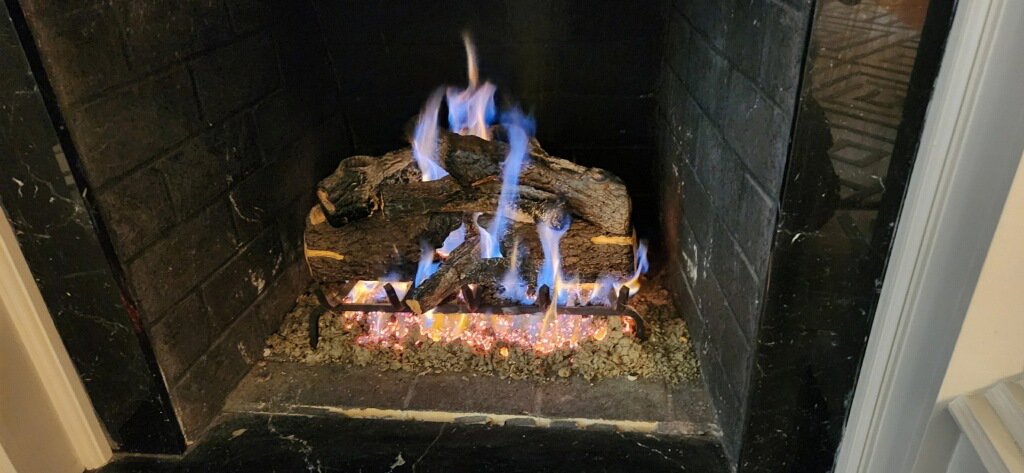A gas fireplace with artificial logs and vibrant blue flames, serviced by Professional Fireplaces and Chimney Sweeps in Huntsville, AL.