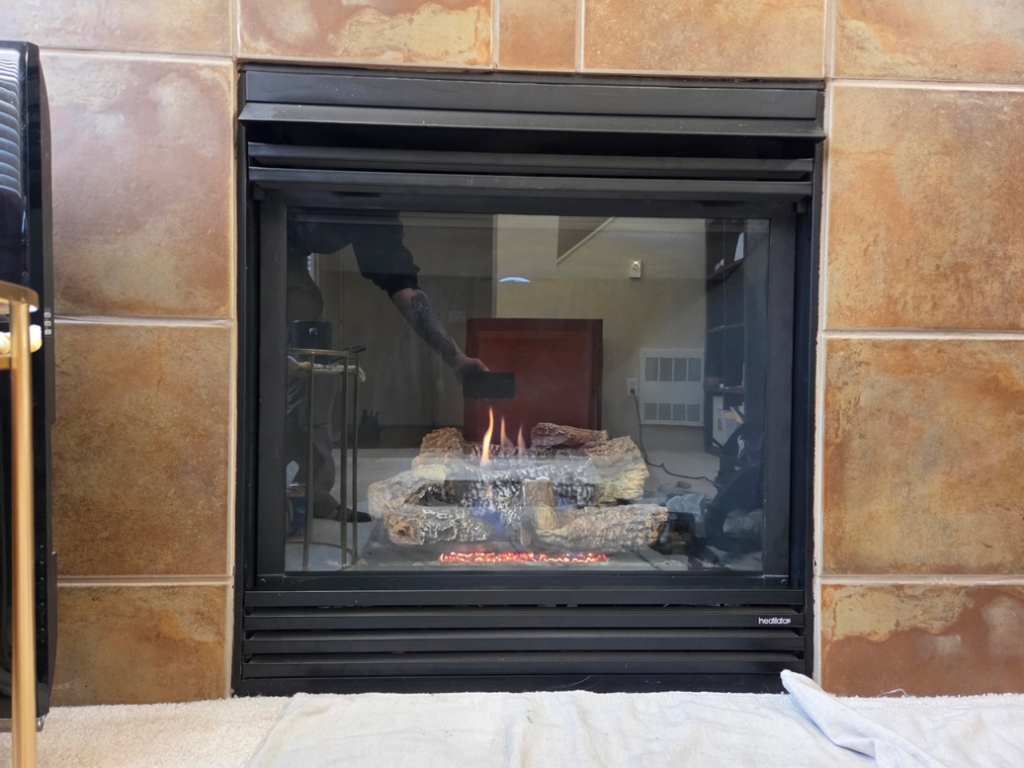 A gas fireplace with active flames and a reflection of a person, showcasing work by Precision Energy LLC in Everett, WA.