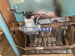 A gas furnace burner assembly with flames during a repair by Wilcox Services in Temple Hills, MD.