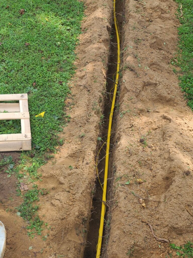A yellow gas line being installed in a trench for an HVAC system by Woodfin-Your Home Team in Richmond, VA.