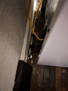 Gas lines, including black rigid pipe and yellow flexible tubing, connected to an appliance, installed by Basurto's Heating & Cooling in Milwaukee, WI.