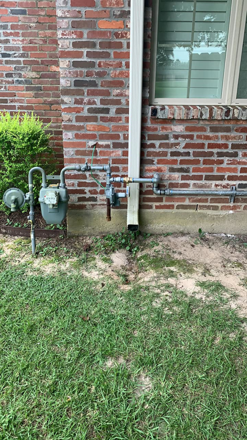 Gas meter and piping installation on a brick house, part of HVAC services by Baton Rouge Air in Baton Rouge, LA