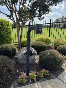 A gate keypad entry system with a black metal fence in the background, installed by HDR Systems Gate, Fence & Garage doors in Plano, TX