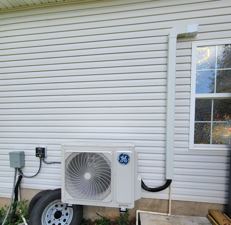 A GE brand outdoor mini-split HVAC unit installed on a house with vinyl siding by Smoky Mountain Ducts & Vents in New Market, TN.
